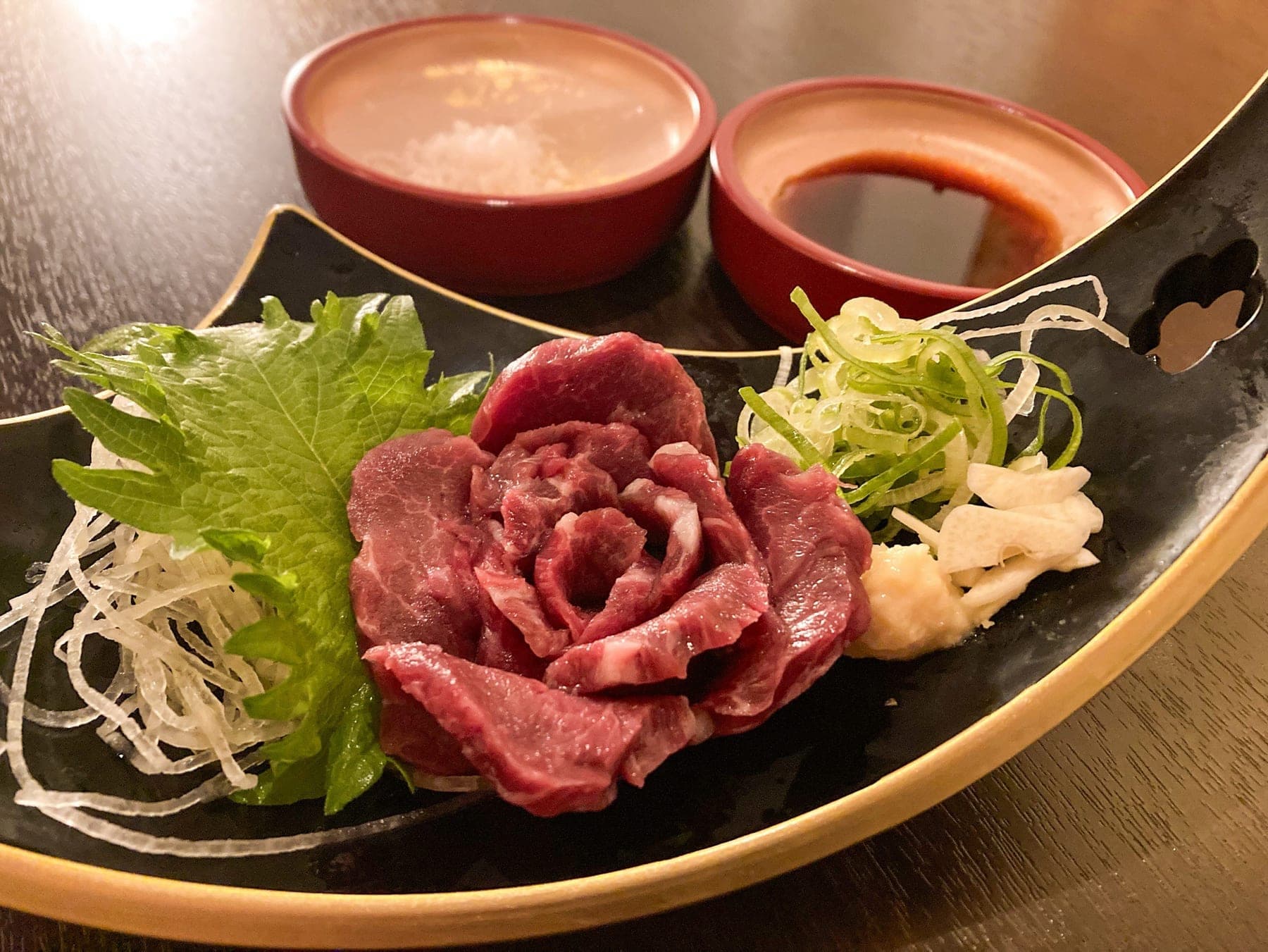 花のように盛り付けた馬刺しの赤身。塩と醤油、二種のつけだれを添えて