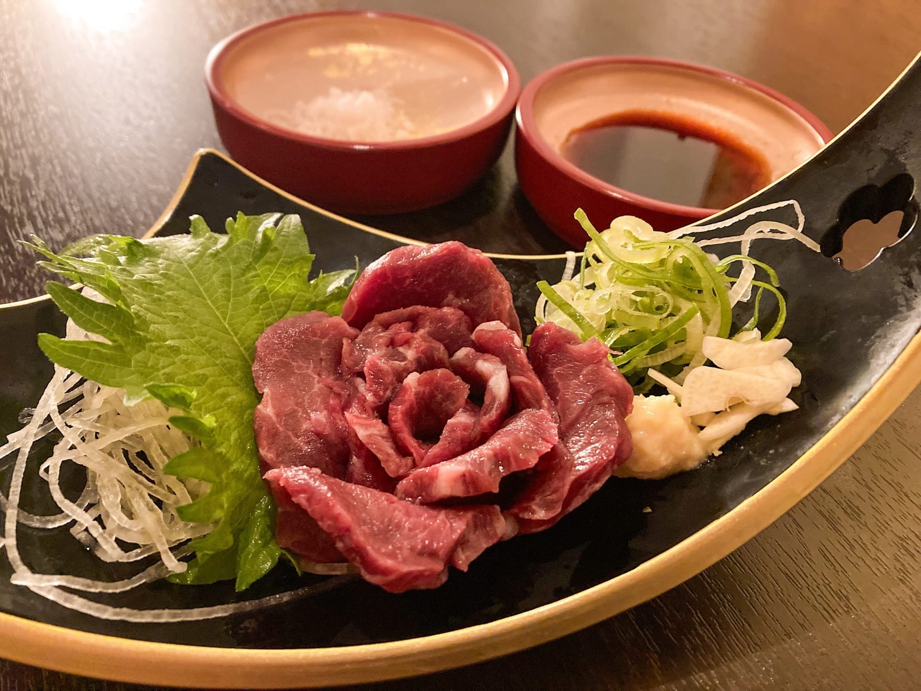 花のように盛り付けた馬刺しの赤身。塩と醤油、二種のつけだれを添えて