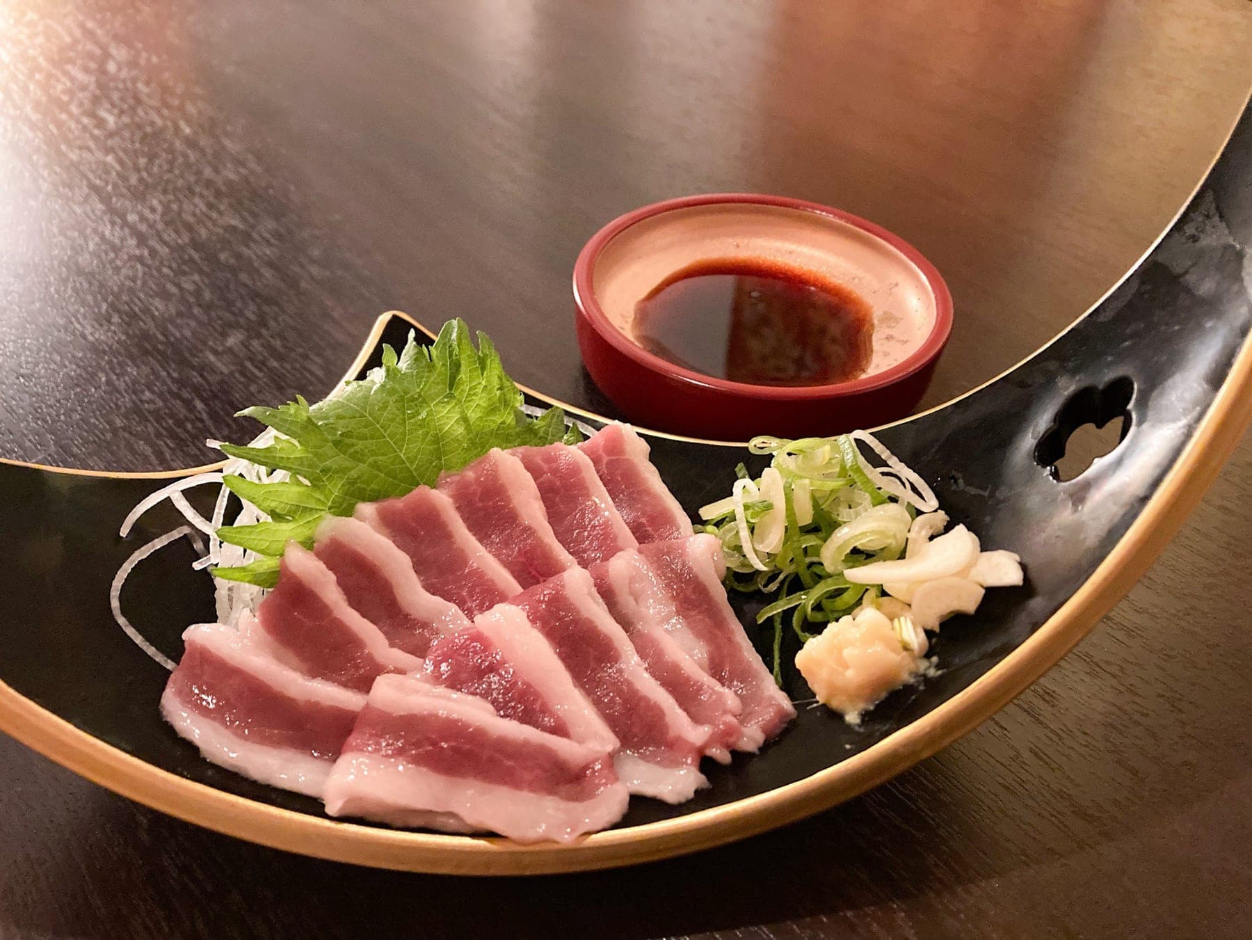 脂の層が美しいバラ系の馬刺し。ねぎとおろしにんにくを添えて