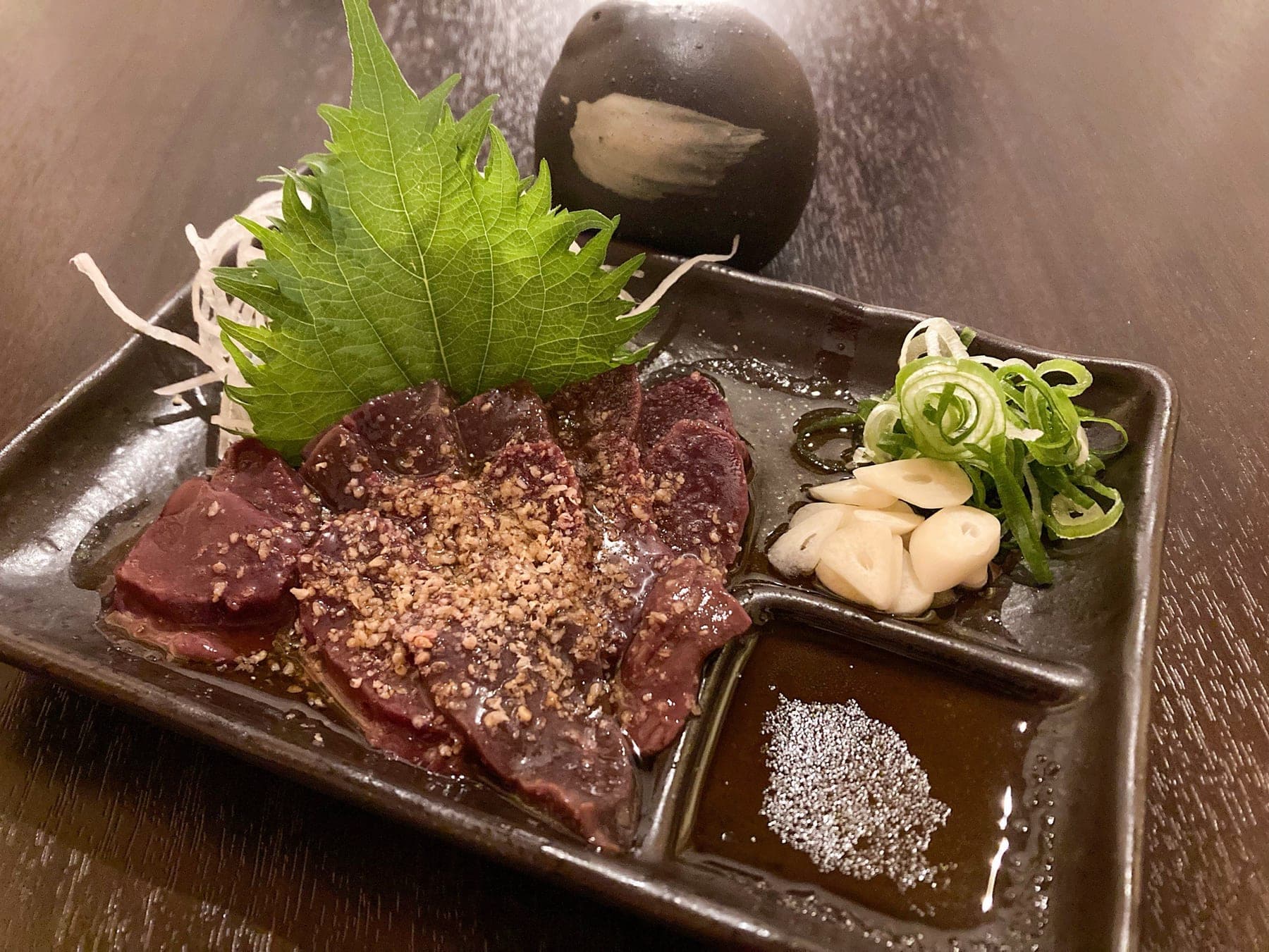 ごま油と塩でいただく馬レバ刺し。にんにくスライスと小ねぎを添えて