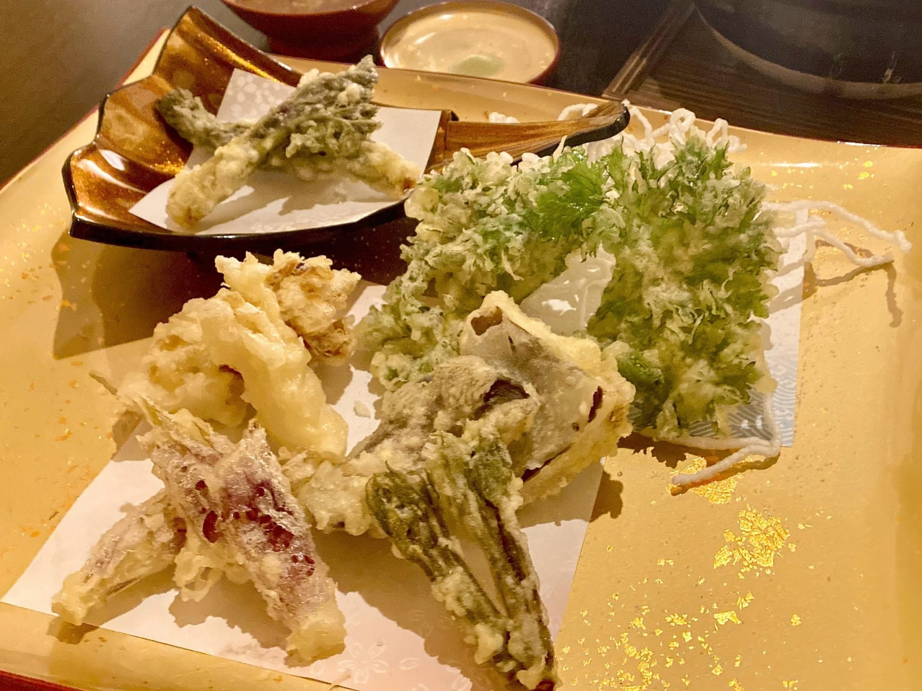 津駅の居酒屋 和ダイニング茉莉の山菜の天ぷら盛り合わせ。金彩の器に旬の山菜が並ぶ